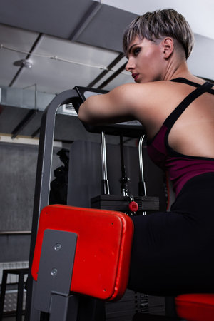Beautiful sport girl is engaged on a simulator in the gym. Pretty girl with the beautiful tightened...
