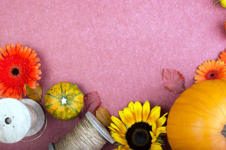 Top view of yellow and orange flowers, rope reel and pumpkins on rose background. Blank greeting card for creative work design. flat layの写真素材
