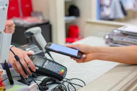 Wireless payment using smartphone and NFC technology. Close up. Female customer paying with smart...