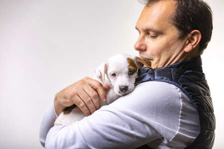 Horizontal portrait of handsome cheerful man holds jack russell terrirer, has glad expressionの写真素材