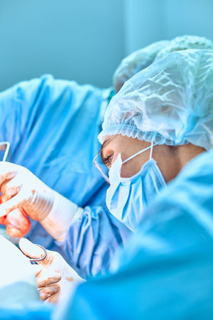 Close up portrait of young female surgeon doctor wearing protective mask and hat during the...