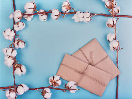 Flat lay of feminine light blue background with branch of cotton flower. Cotton, gift boxes, jute rope hank. Flat lay, copy space.の写真素材