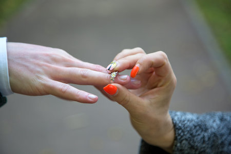 Close-up Of Womans Hand Putting Golden Ring On Mans Finger