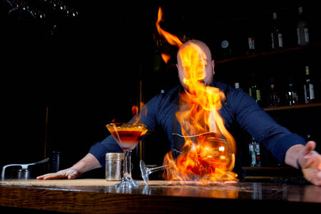 Fiery show at the bar. The bartender makes hot alcoholic cocktail and ignites bar. Bartender...