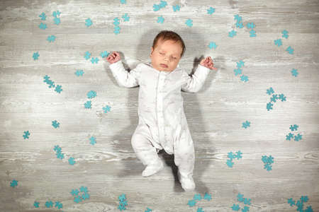 Newborn baby quietly sleeps on a wooden floor blue puzzles around. Calm and healthy sleep in newborns.の写真素材