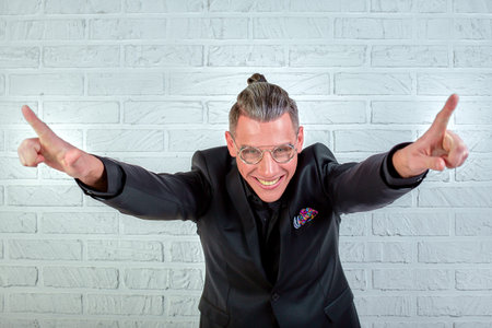 Close up portrait of a happy young businessman wearing glasses dressed in a black suit shows hands coolの写真素材