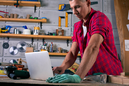 worker at his workplace work with notebook while and standing at factory workshop