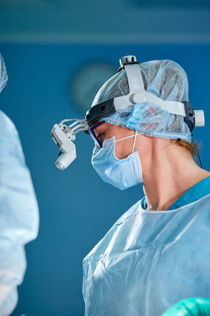 Close up portrait of female surgeon doctor wearing protective mask and hat during the operation....