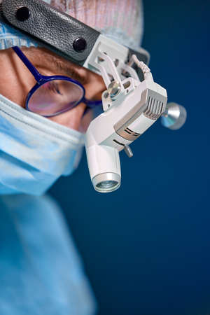 Close up portrait of female surgeon doctor wearing protective mask and hat during the operation. Healthcare, medical education, surgery concept.の写真素材