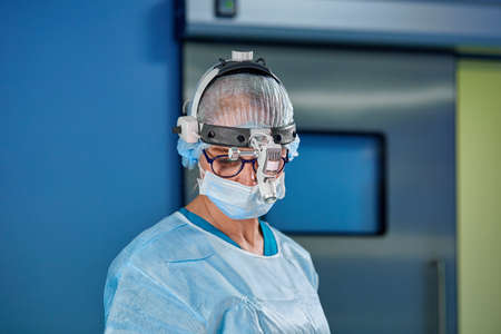 Close up portrait of female surgeon doctor wearing protective mask and hat during the operation. Healthcare, medical education, surgery concept.の写真素材