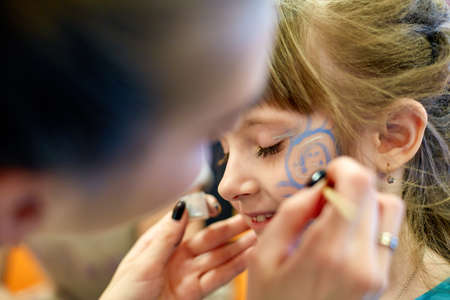 woman painting face of kid outdoors. baby face paintingの写真素材