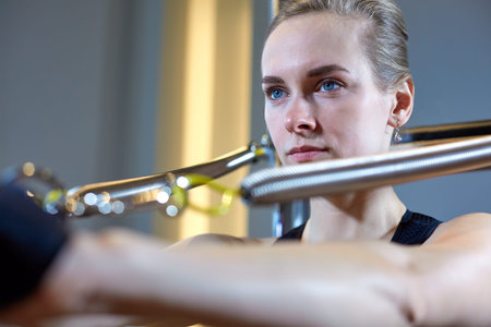 gym woman pilates stretching sport in reformer bed instructor girl. Selective focus on hands