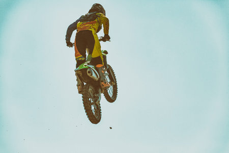 A picture of a biker making a stunt and jumps in the air