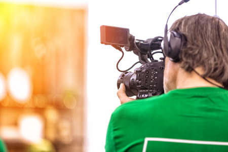 The concept of the creation of TV, video content, backstage. A professional cameraman is filming on a video camera. Backstage of the TV show filming process. Copy spaceの写真素材