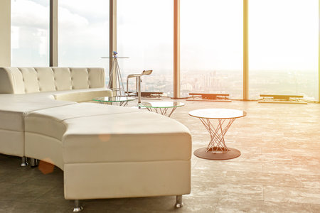 High end design in a skyscraper, a sofa, tables with a view to the view windows and the city
