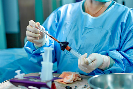 Hands hold syringes to carry fat during work. The operation to transfer fat from one part of the...
