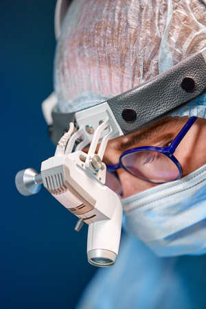 Close up portrait of female surgeon doctor wearing protective mask and hat during the operation. Healthcare, medical education, surgery concept.の写真素材