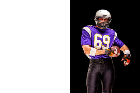 American football player in motion with the ball on a black background with a light line, copy space.の写真素材