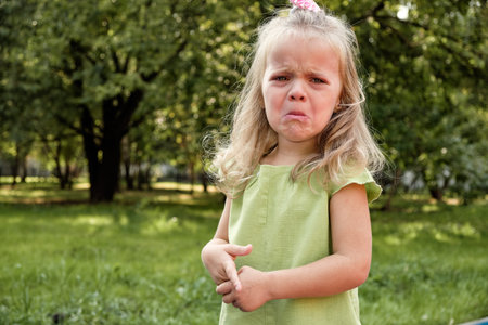 Upset girl child crying in the park. Parenting, child psychology.