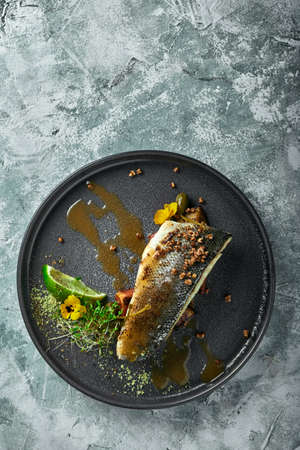 Grilled seabass with eggplant and lime. Horizontal top view, top shot. Copy space, gray concrete marble background, soft light. Food Fashion Photo.の写真素材