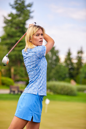Portrait of a beautiful woman playing golf on a green field outdoors background. The concept of golf, the pursuit of excellence, personal excellence, royal sport.の写真素材