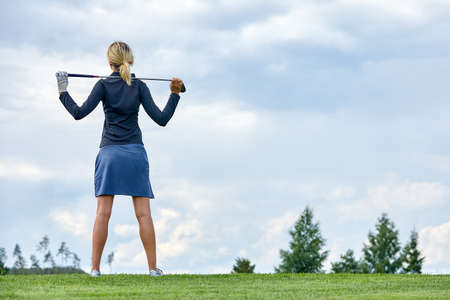 Goal concept, copy space. Women golfing time holding golf equipment on green field background. The pursuit of excellence, personal craftsmanship, royal sport, sports banner.の写真素材
