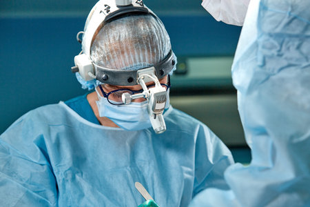 Close up portrait of female surgeon doctor wearing protective mask and hat during the operation. Healthcare, medical education, surgery concept.の写真素材