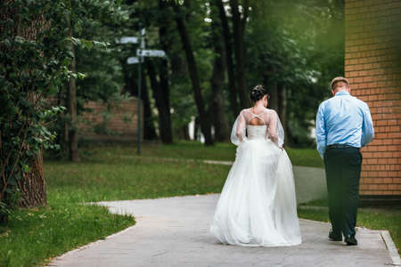 Bride and groom at wedding Day walking Outdoors on spring nature. Bridal couple, Happy Newlywed woman and man embracing in green park. Loving wedding couple outdoor. Bride and groomの写真素材