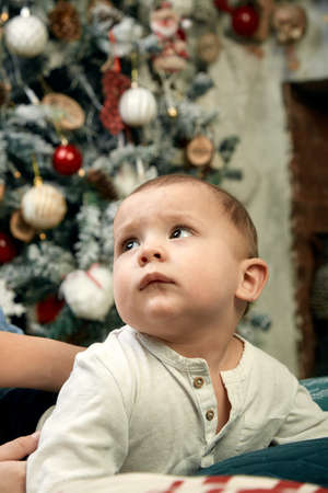 Beautiful little boy dreaming of cottages under the Christmas tree. Christmas concept and children waiting for a miracle.の写真素材