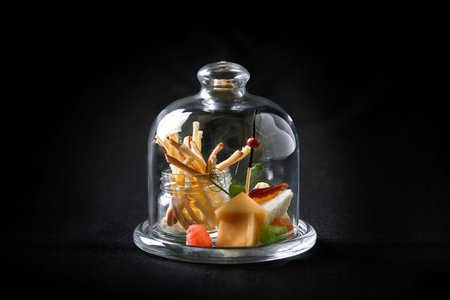 Assorted cheeses with berries and marmalade, mini serve in a glass flask. Fusion food concept, low key, copy spaceの写真素材