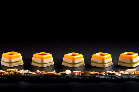 Colored marmalade, laid out in a beautiful line on a black plate. food background. Fusion food concept, low key, copy space.の写真素材
