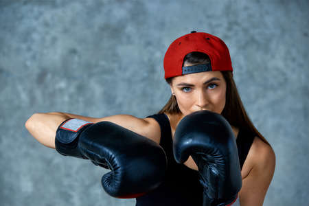 Beautiful athletic girl posing in pink boxing gloves on a gray background. Copy space. Concept sport, fight, goal achievement.の写真素材