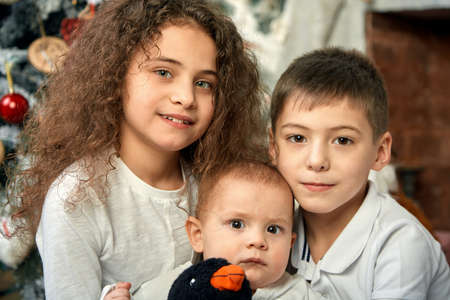 Christmas concept and children waiting for a miracle. Portrait of different kids on the background of Christmas decor, 15 minutes before Christmas Eve. Children awaiting Christmas and gifts, copy space.の写真素材