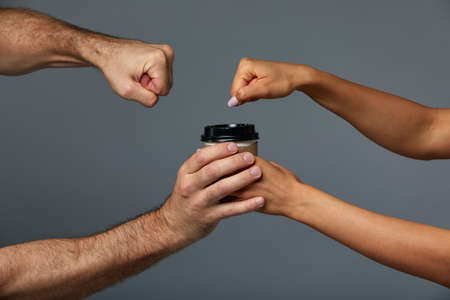 Female and male hand mock paper cup with tea or coffee drink, on isolate gray background. Gray background, copy space.の写真素材