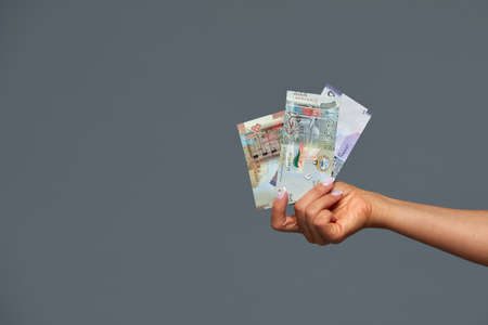 Beautiful female hands hold Kuwaiti dinars on a gray background. Copy space, gray background.の写真素材