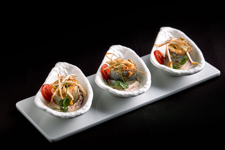 rolls of sea bass baked stuffed with vegetables and mushroom sauce, on a dark background, copy...