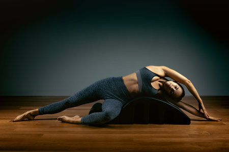 Pilates, fitness, sport, training and people concept - woman doing exercises on a small barrel....