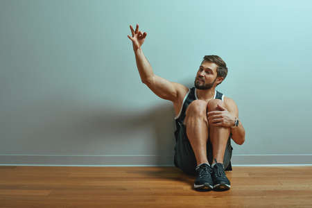 Portrait of caucasian handsome man smile wearing t-shirt posing against studio wall pointing with index fingers at copy space for advertismentの写真素材