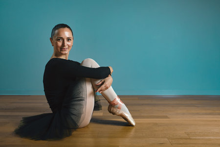 pretty woman ballerina in tutu and pointe in black swimsuit posing in studio on blue backgroundの写真素材
