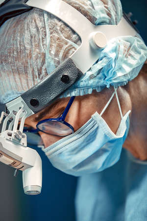 Close up portrait of young female surgeon doctor wearing protective mask and hat during the operation. Healthcare, medical education, surgery conceptの写真素材