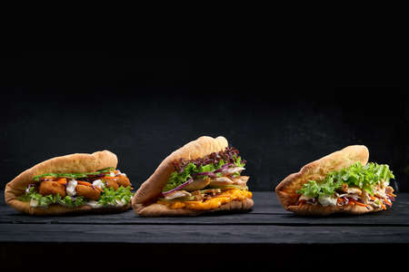 Closeup of three different Appetizing sandwiches burgers on black wooden backgroundの写真素材