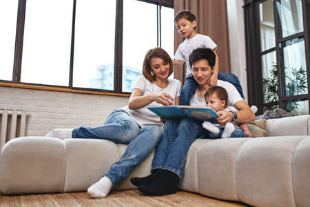 Happy international family concept. Dad, mom, son and little daughter posing for a camera at home, are engaged in home parenting. Home holidays, parenting, concept children and parents.の写真素材