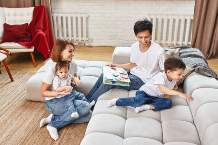 Happy international family concept. Dad, mom, son and little daughter posing for a camera at home,...