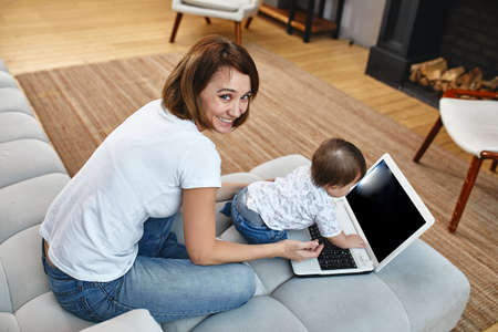 Inventive modern mother with children multitasking in the morning. Mom and baby are modern technologies and gadgets. work at home in the divert.の写真素材
