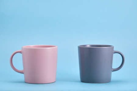Pink and blue mug on a blue background. The struggle of opposites, the game of color.の写真素材