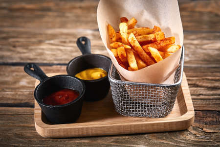 French fries with ketchup and mustard, wooden background, side dish, traditional American food.の写真素材