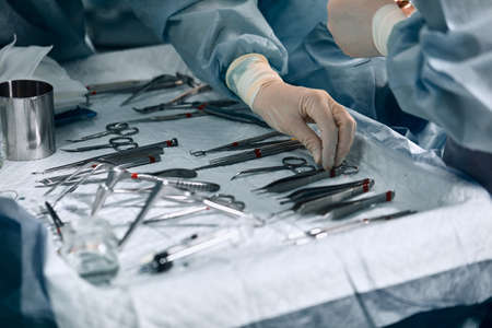 The surgeons hands are holding an operating tool in the operating room. Close-up, beautiful light,...