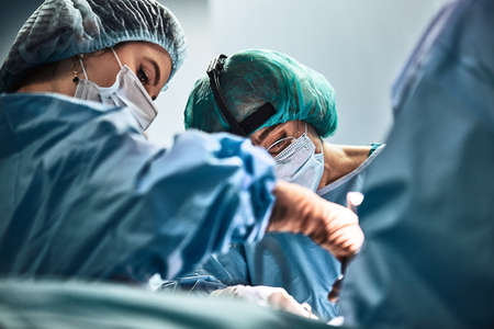 A surgeon s team in uniform performs an operation on a patient in the clinic of the center.の写真素材