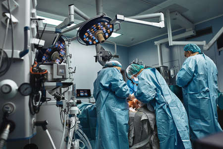 A team of professional surgeons works in the operating room. A real operation to remove a cancerous tumor. Life saving, modern operating room. Fight for lifeの写真素材