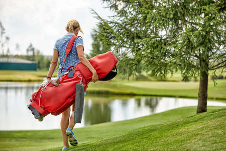 Golf concept, copy space. Women golf time holding golf equipment on green field background. The pursuit of excellence, craftsmanship, royal sport, sports banner.の写真素材